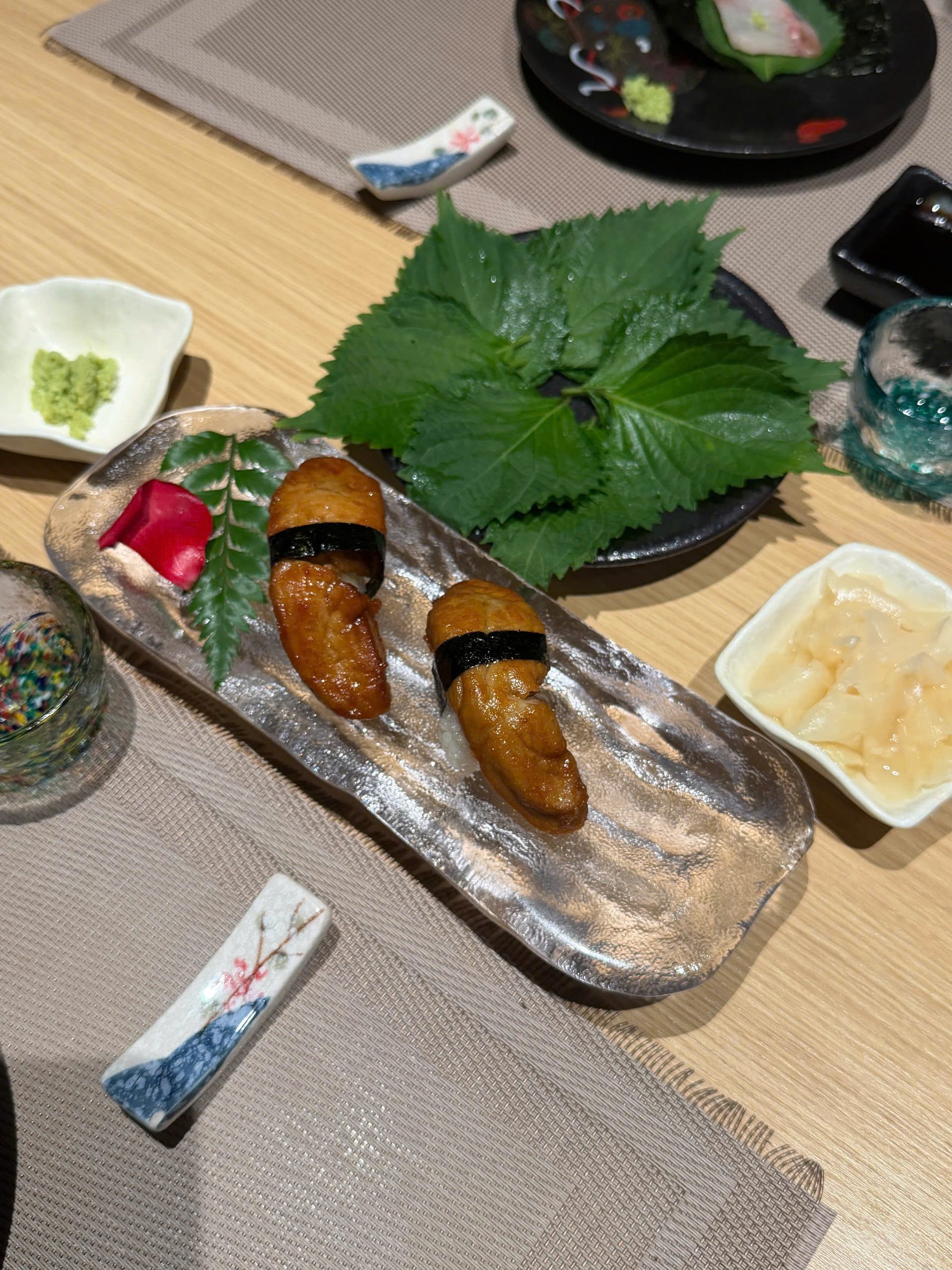 Hai miếng sushi foie gras phủ sốt xì dầu và cố định bằng dải rong biển