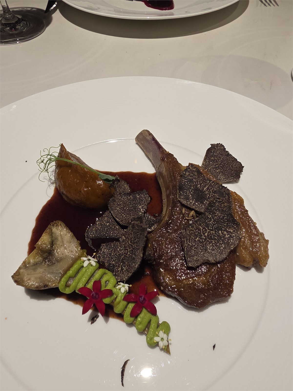 Đĩa lamb rack của tác giả với nấm truffle bào, sốt sẫm màu, rau củ và hoa ăn được