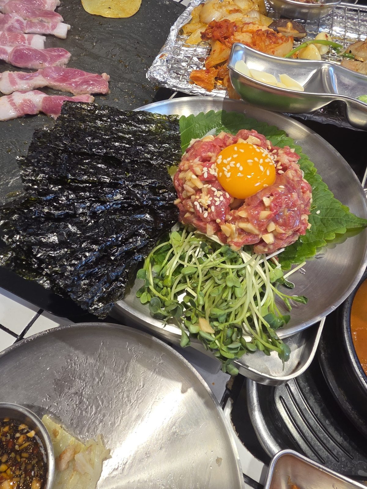 Đĩa yukhoe với lòng đỏ, lê, rau mầm và rong biển tẩm gia vị được tặng trong lúc gọi chai soju thứ hai